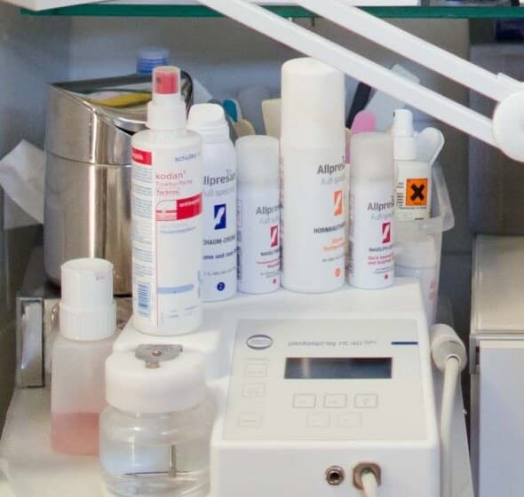 Fußpflegegerät mit Display vor einer Reihe Pflegeschäume und Sprays im Regal